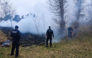 policjanci gaszą pożar łąki