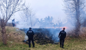 policjanci gaszą pożar łąki