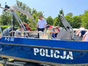 Dzieci w towarzystwie policjanta na łodzi policyjnej