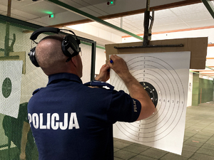 policjant zlicza punkty na podstawie oddanych strzałów do tarczy strzeleckiej
