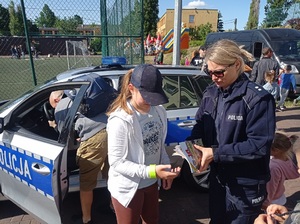 Funkcjonariuszka rozmawia z dzieckiem nt. bezpieczeństwa w RD i przekazauje elementy odblaskowe oraz książęczkę o bezpieczeństwie w RD