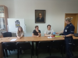 Policjantka rozdaje studentom ulotki informacyjne dla kandydatów do służby w Policji