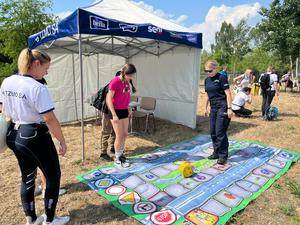 policjantka stoi na macie edukacyjnej, ukazującej fragment drogi