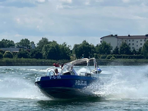 policjant, siedząc za sterem łodzi policyjnej patroluje akwen