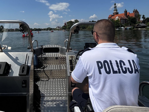 policjant ,siedząc za sterem łodzi policyjnej patroluje akwen