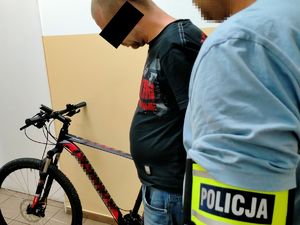 nieumundurowany policjant i zatrzymany mężczyzna stoją przy zabezpieczonym rowerze