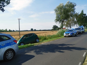 samochód osobowy marki Mercedes stoi poza jezdnią wzdłuż drogi, przed i za pojazdem znajdują się radiowozy.