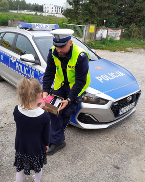 policjant wręcza dziecku opaskę odblaskową
