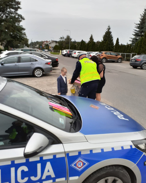 policjant wręcza dzieciom opaski odblaskowe