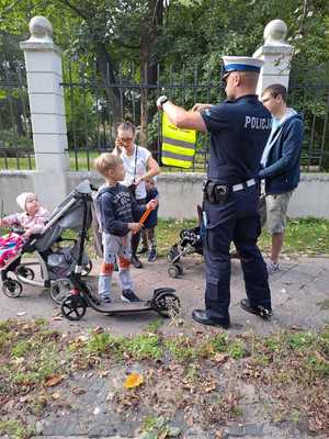 Policjant przekazuje elementy odblaskowe przechodniom