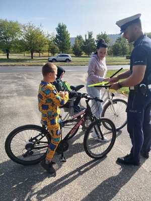 Policjant przekazuje elementy odblaskowe przechodniom