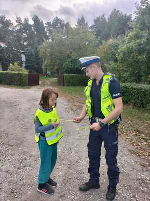 Policjant przekazuje elementy odblaskowe przechodniom