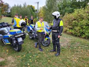 Policjant przekazuje elementy odblaskowe dzieciom