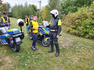 Policjant przekazuje elementy odblaskowe dzieciom