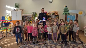 na zdjęciu widzimy dzieci oraz policjantkę wydziału ruchu drogowego. Policjantka omawia z dziećmi zasady bezpiecznego poruszania się po drodze.