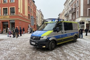 Na zdjęciach widzimy policjantów oraz wolontariuszy WOŚP.  Zdjęcia wykonane są na toruńskiej starówce oraz w Dowrze Artusa. Na zdjęciach widać policyjne radiowozy, umundurowanych policjantów.