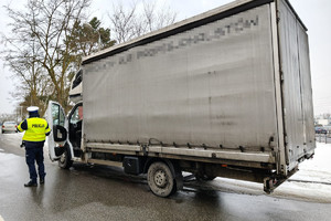 na zdjęciu widzimy policjanta ruchu drogowego dokonującego kontroli pojazdu dostawczego