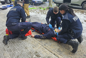 Na zdjęciu widać umundurowanych policjantów udzielających pierwszej pomocy medycznej. Są to szkolenia z kursu kwalifikowanej pierwszej pomocy medycznej.