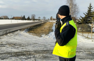 Na zdjęciach widać umundurowanego policjanta dokonującego pomiaru prędkości. Na kolejnych fotografiach umundurowany policjant przeprowadza kontrole drogową przy zatrzymanym samochodzie osobowym.