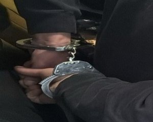 Na zdjęciu widzimy dłonie osoby z założonymi kajdankami na ręce trzymane z tyłu.