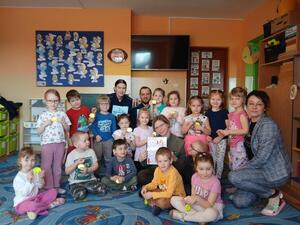 Na zdjęciach widać umundurowanych funkcjonariuszy policji. Prowadzą zajęcia w grupie przedszkolaków. Na jednym ze zdjęć grupa dzieci jest przy oznakowanym policyjnym radiowozie. Kolejne zdjęcia przedstawiają dzieci w trakcie zajęć.