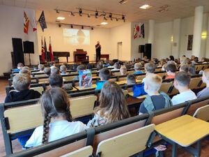 na zdjęciach widać umundurowanego policjanta prowadzącego zajęcia w szkole. Na dwóch pozostałych zdjęciach widać uczniów, bez widocznych twarzy.