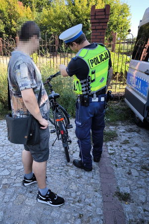 Na zdjęciu widać umundurowanego policjanta przeprowadzającego kontrolę w ruchu drogowym