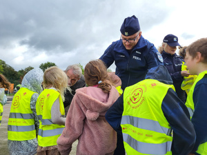 na zdjęciach znajdują się przedstawiciele Policji oraz innych służb mundurowych w trakcie przekazywania odblaskowych kamizelek dzieciom.