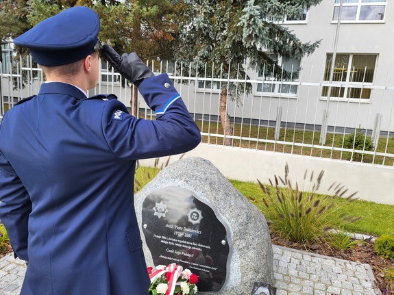 Policjanci składają wieniec i oddają honor poległemu funkcjonariuszowi
